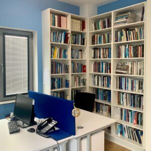 An office with 2 computers and 2 desks with 2 full bookshelves